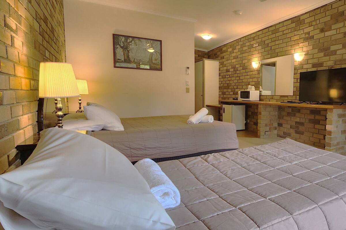 A hotel room with a large bed, a desk with a chair, a television, and a microwave.