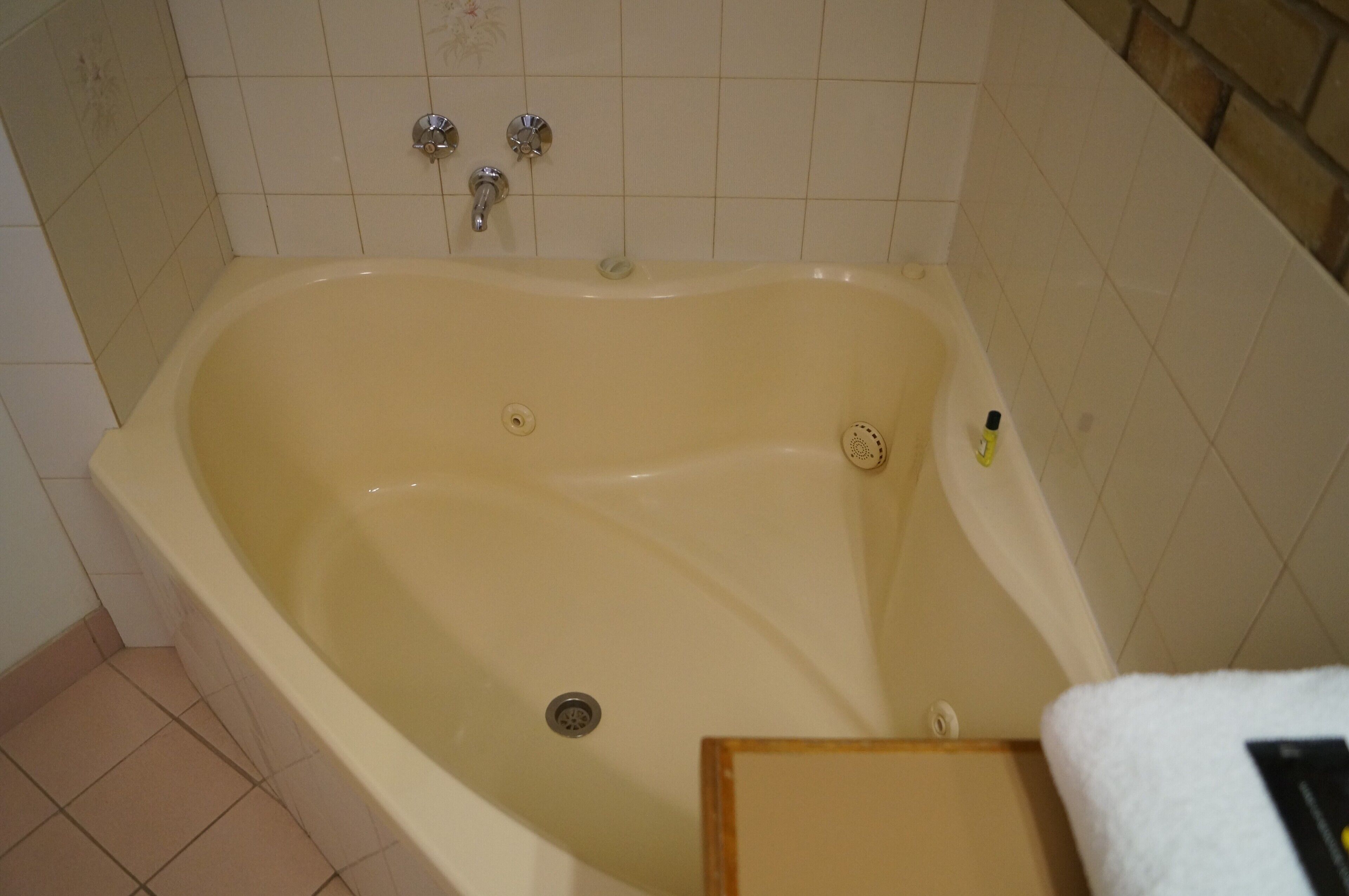 Una bañera con desagüe, grifo y dispensador de jabón.