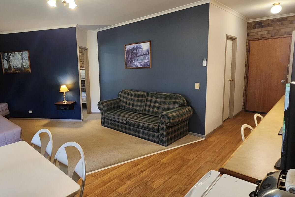 A room with a bed, a sofa, a dining table, and a TV.