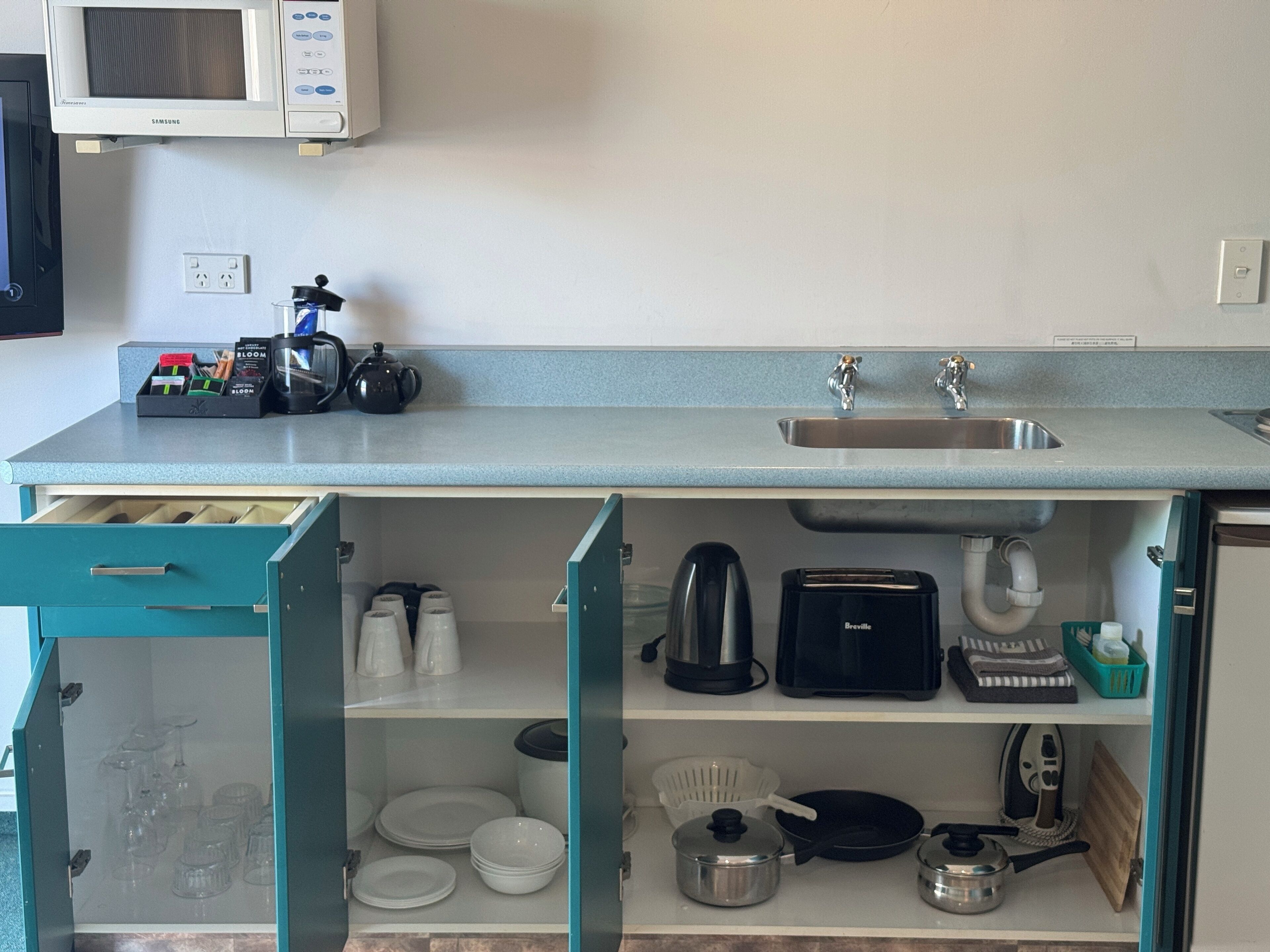 Una cocina compacta equipada con microondas, lavamanos y diversos electrodomésticos.