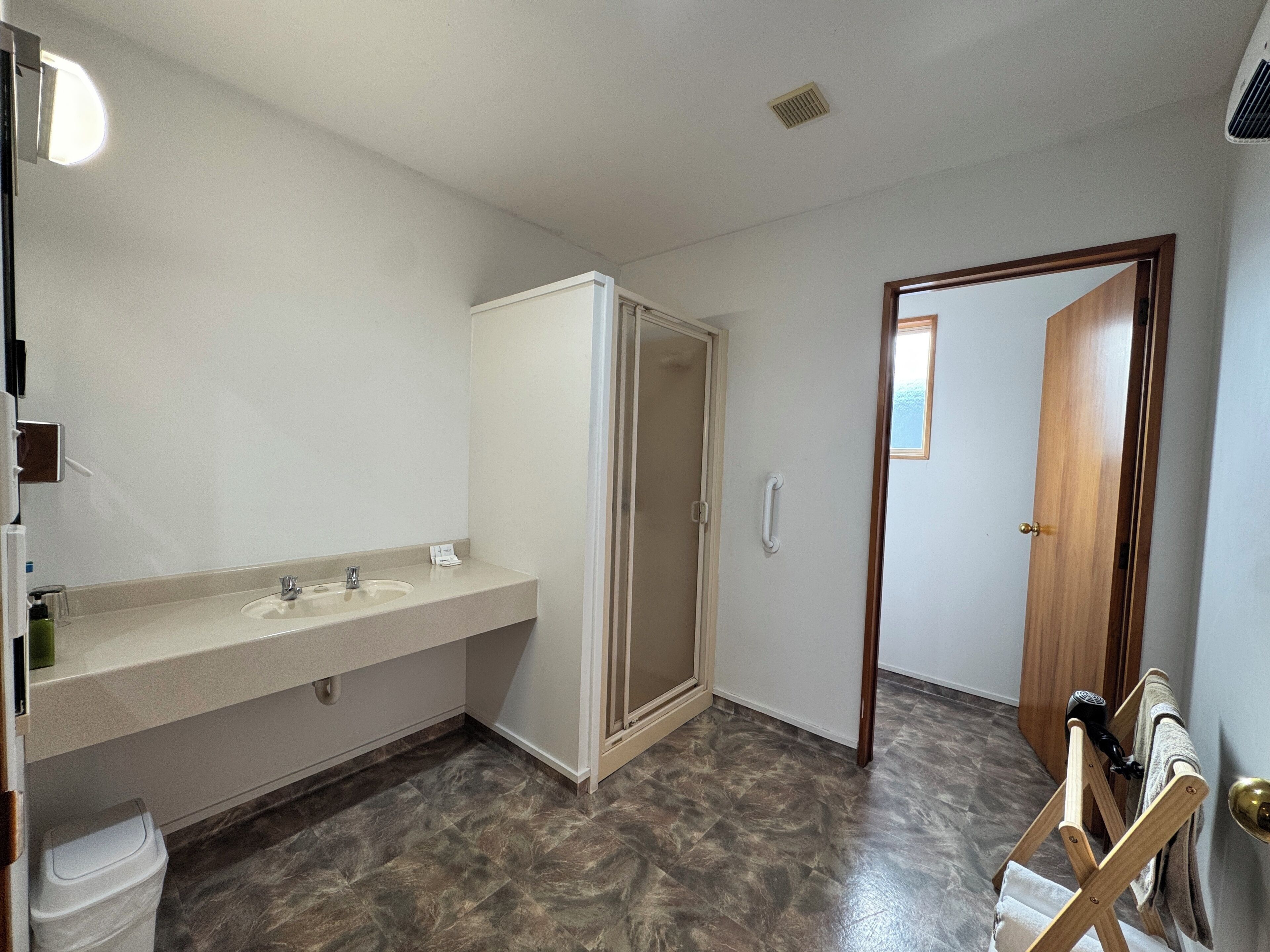 A bathroom with a sink, mirror, and shower.