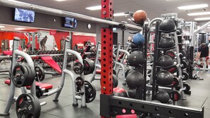 Un gimnasio con equipo de levantamiento de pesas, cintas de correr y balones de ejercicio.