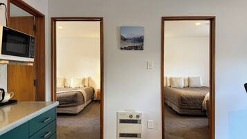 A hotel room with a bed, a microwave, a small heater, and a picture on the wall.