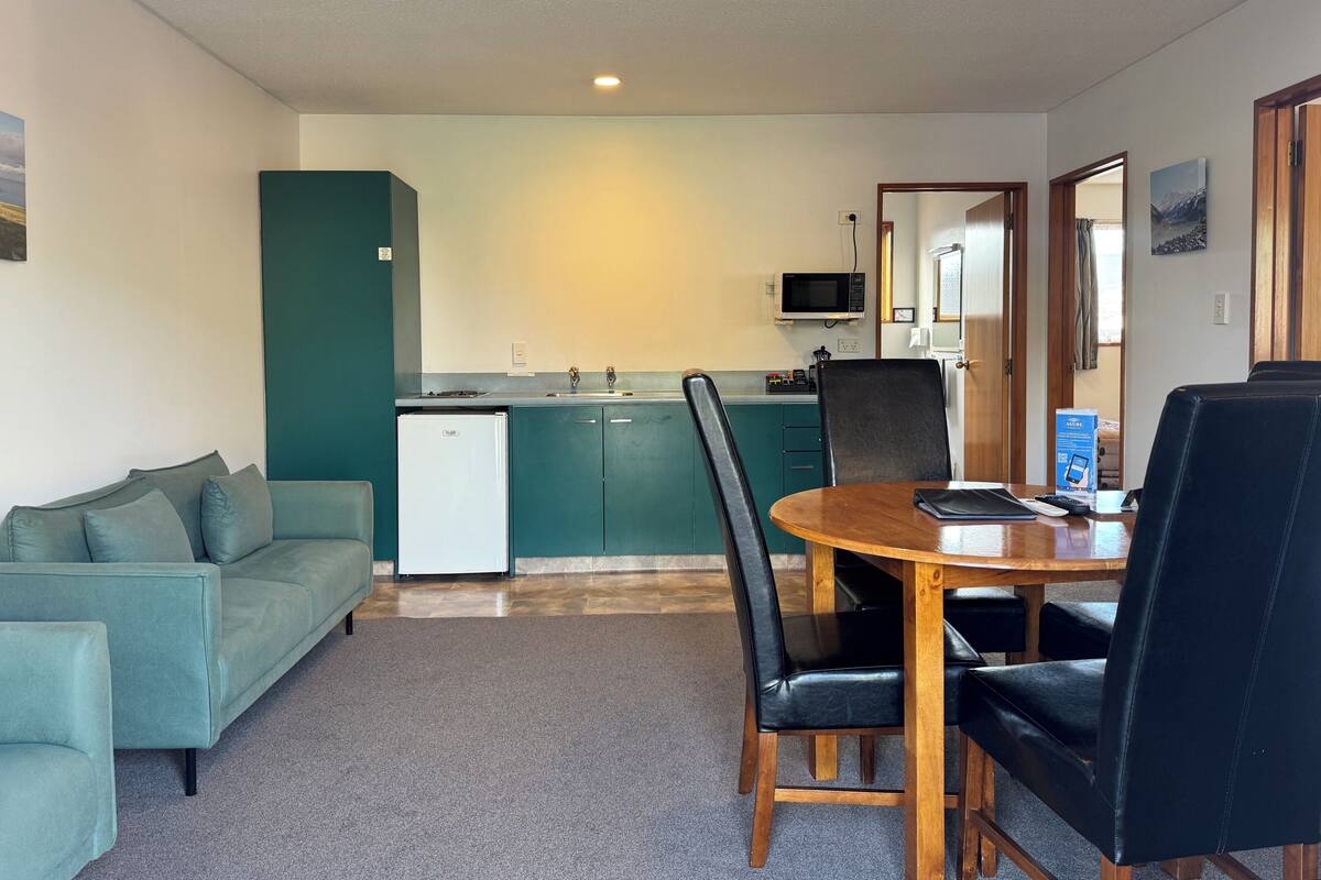 A compact living space with a kitchenette, a dining area with a table and chairs, and a sofa.