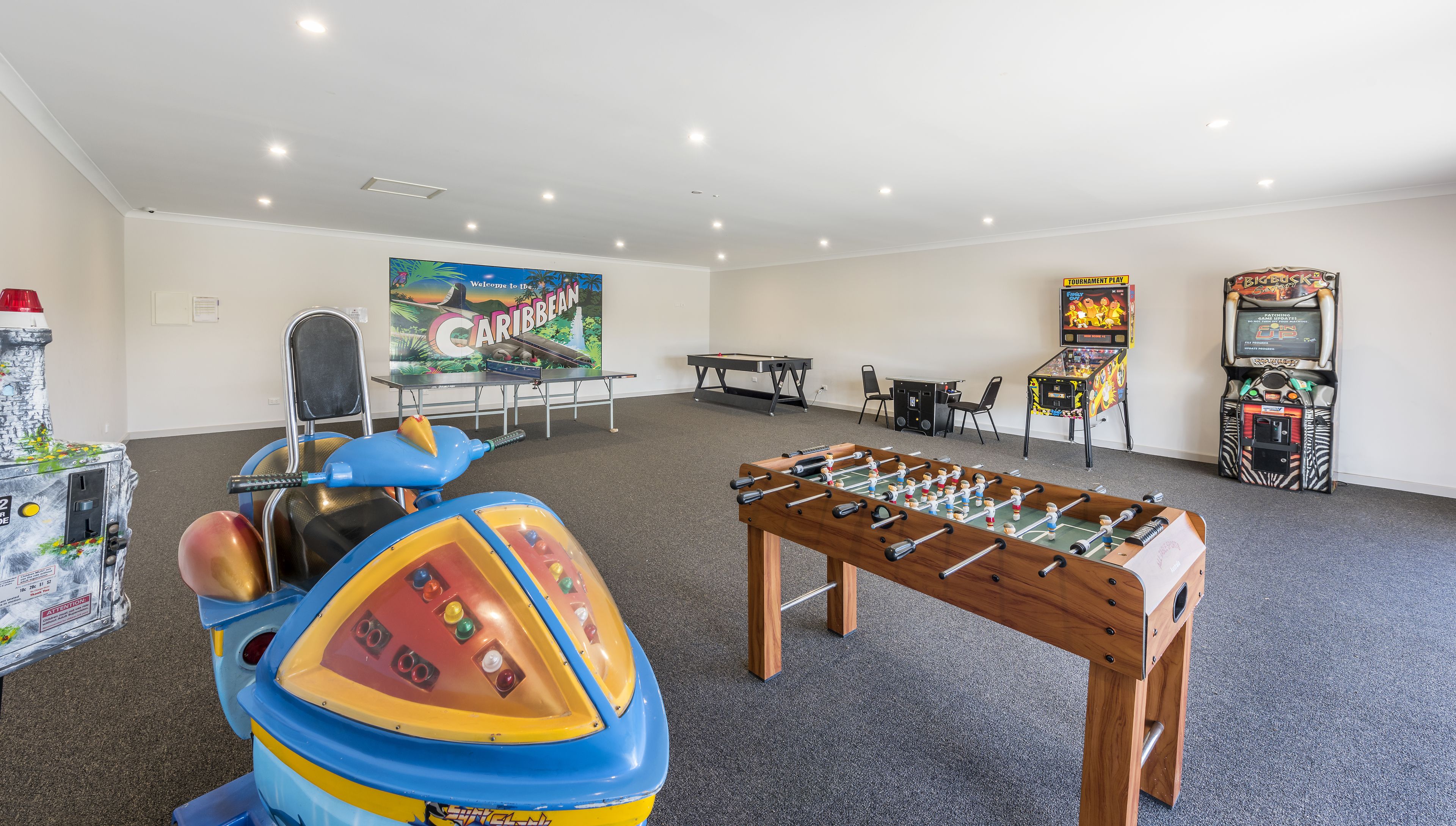 Una habitación con mesa de futbolín, juegos de arcade y un mural colorido.