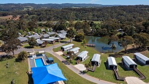 Vista aérea de un camping con vehículos recreativos, una piscina y un lago.