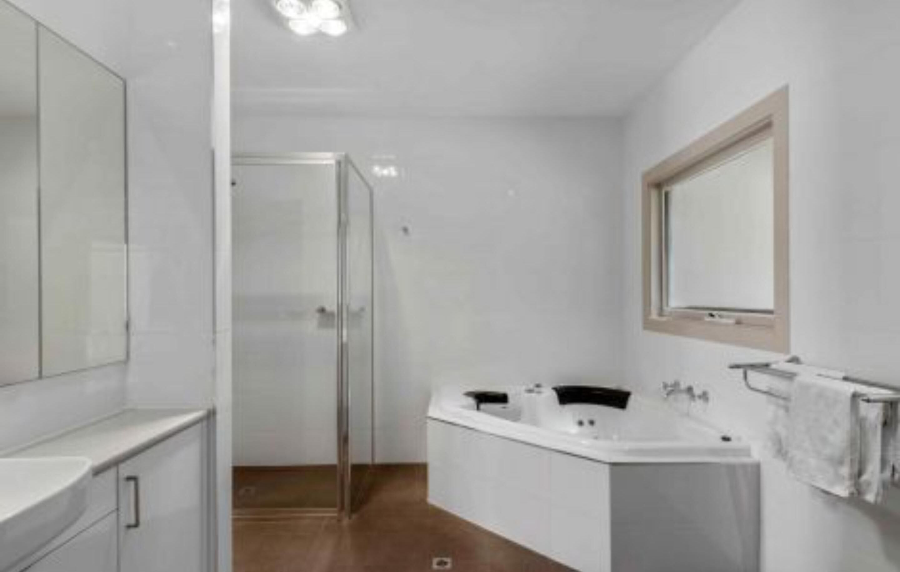 Un baño moderno con cabina de ducha, bañera independiente y un espejo grande.