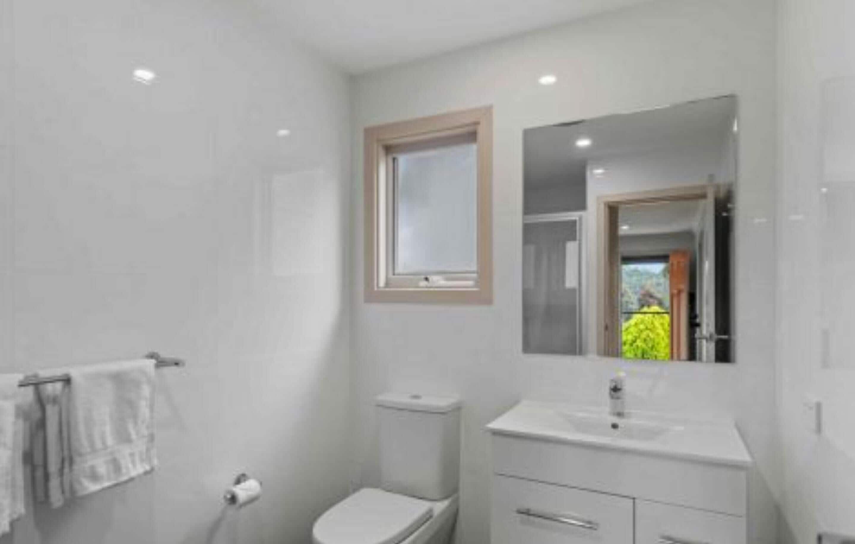A modern bathroom with a toilet, sink, and mirror.