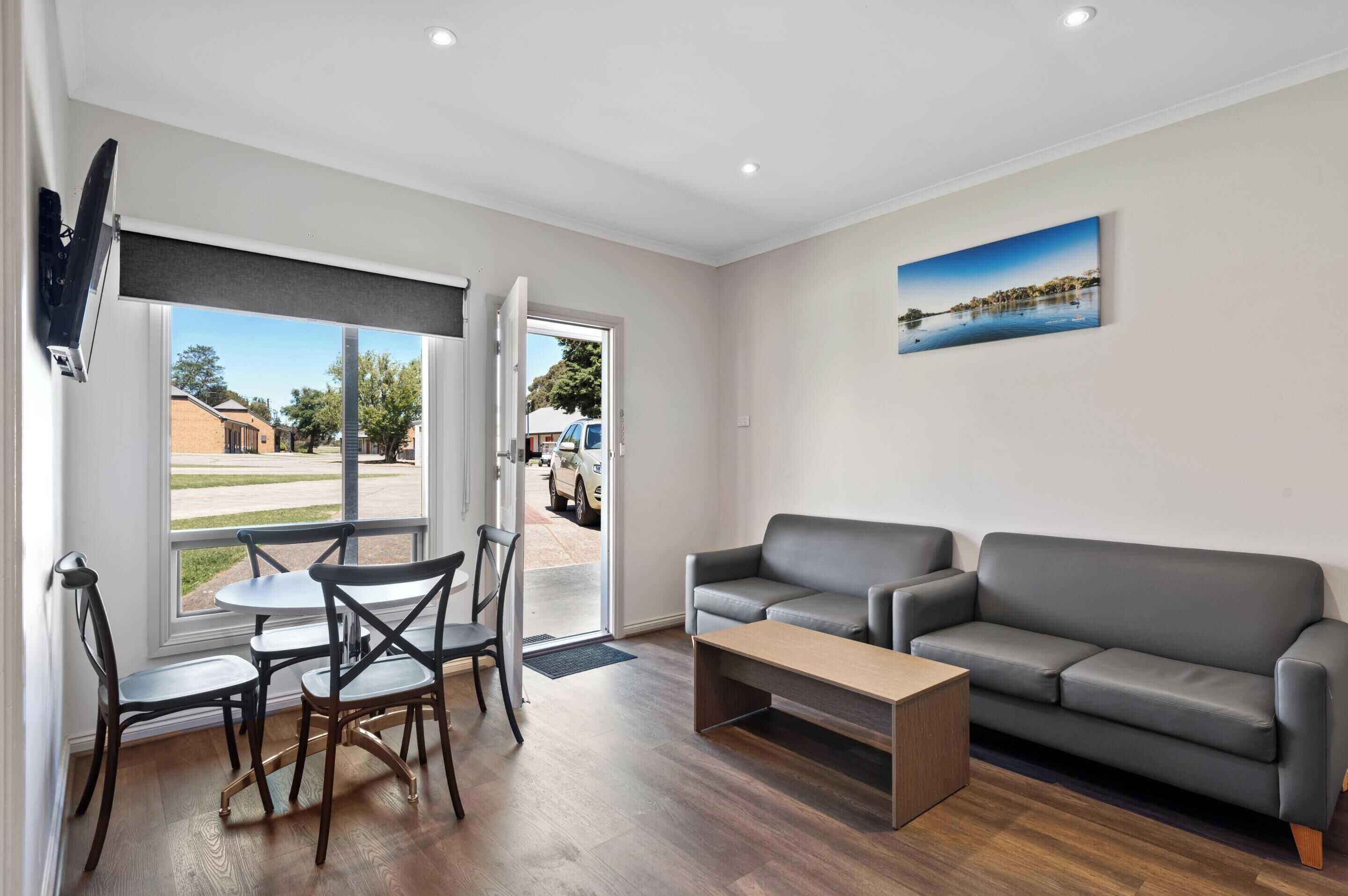 A modern living room with a grey sofa, a coffee table, and a dining area with chairs and a table.