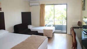 A hotel room with two beds, a sofa, a dining table, and a TV. - Centenary Motor Inn (Oxley)