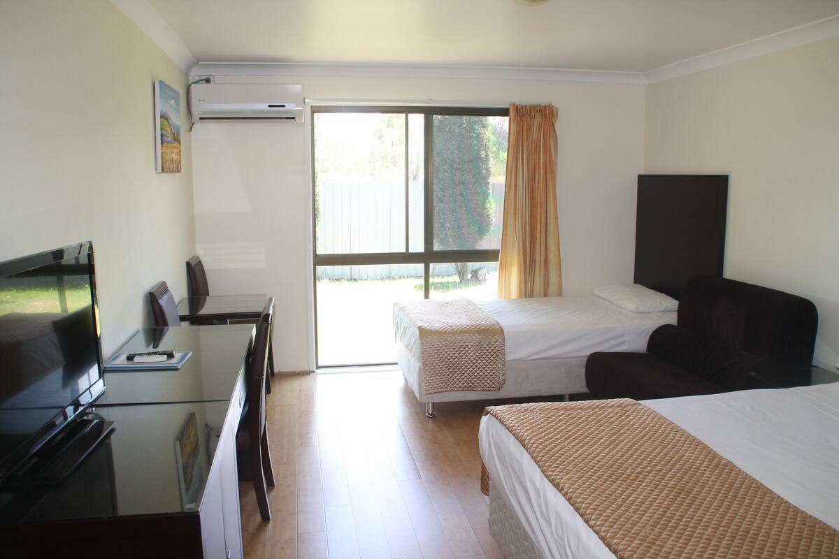 A hotel room with a bed, a desk with a TV, and a chair.