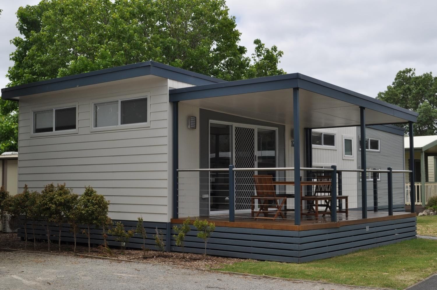 A modern, single-story mobile home with a covered porch and a small deck.