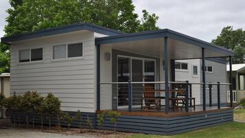 A modern, single-story mobile home with a covered porch and a small deck.