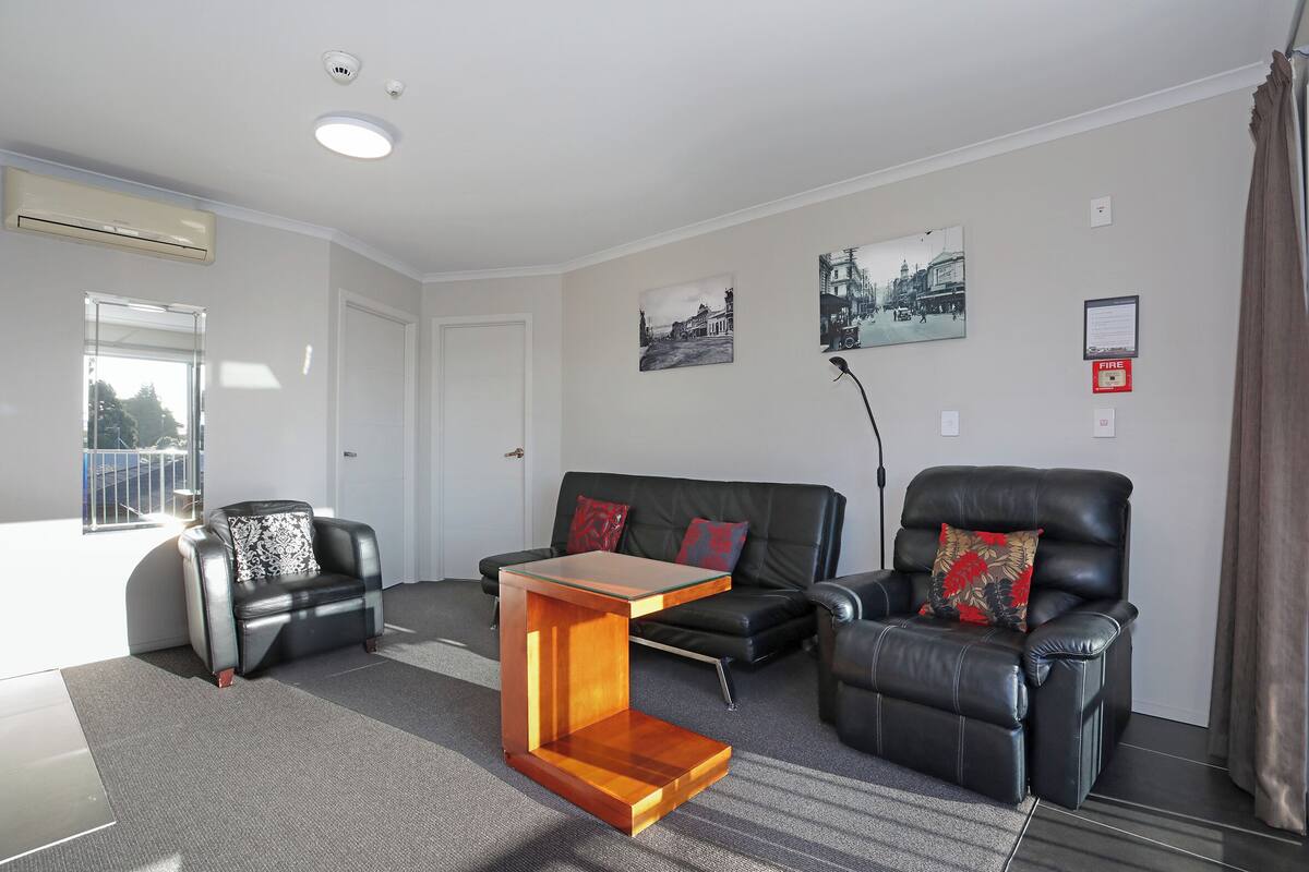 A modern living room with a sofa, two armchairs, a coffee table, and a fireplace.