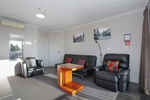 A modern living room with a sofa, two armchairs, a coffee table, and a fireplace. - City Corporate Motor Inn (Palmerston North)