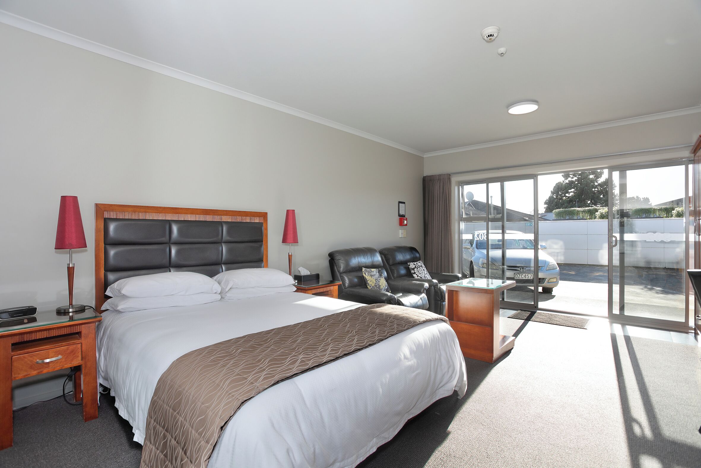 Habitación de hotel con una cama grande, un escritorio, una silla y vistas al exterior.