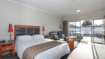 Habitación de hotel con una cama grande, un escritorio, una silla y vistas al exterior.