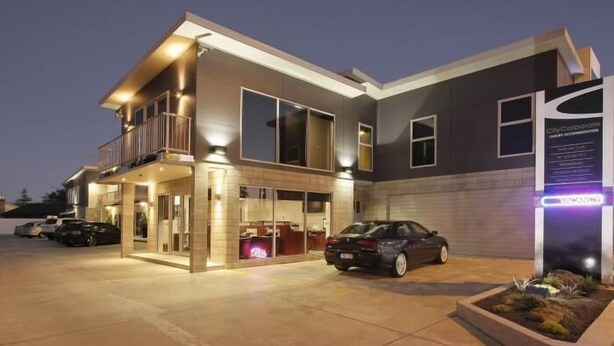 A modern hotel with a two-story structure, a covered entrance, and a parking area with cars. - City Corporate Motor Inn (Palmerston North)
