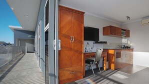 A modern kitchen with wooden cabinets, a microwave, and a flat-screen TV. - City Corporate Motor Inn (Palmerston North)