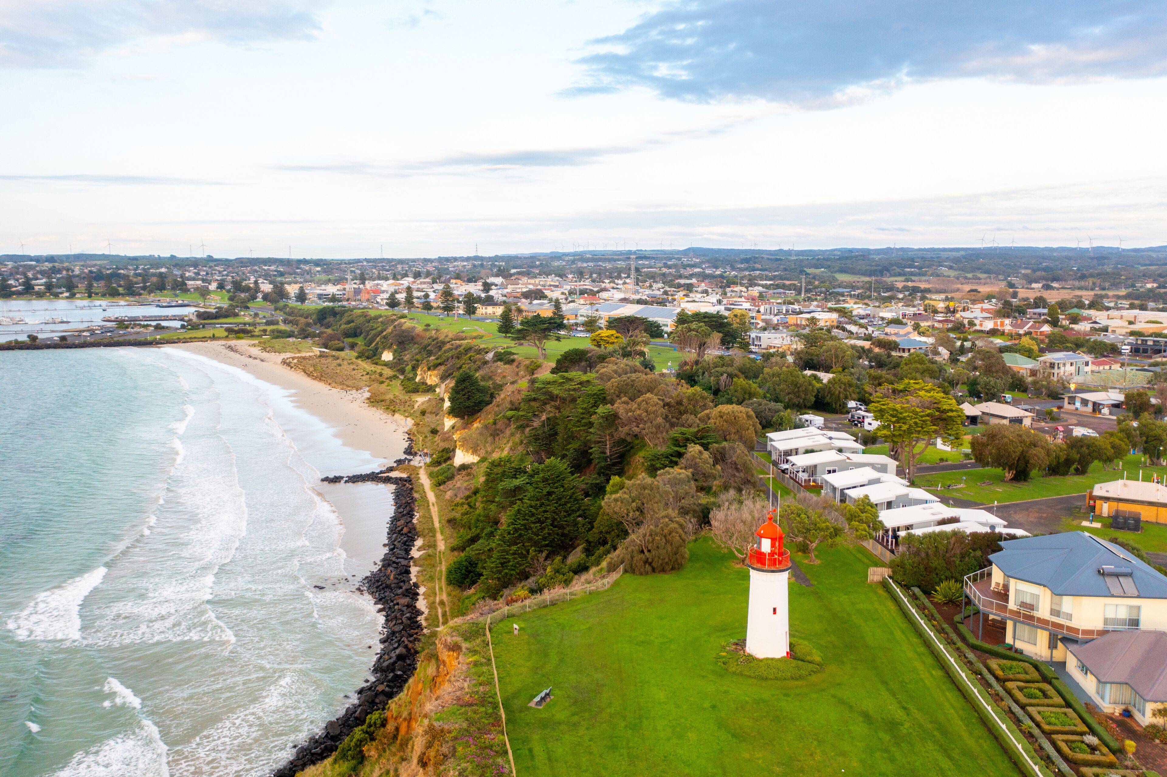 A coastal town with a lighthouse, beach, and residential area.