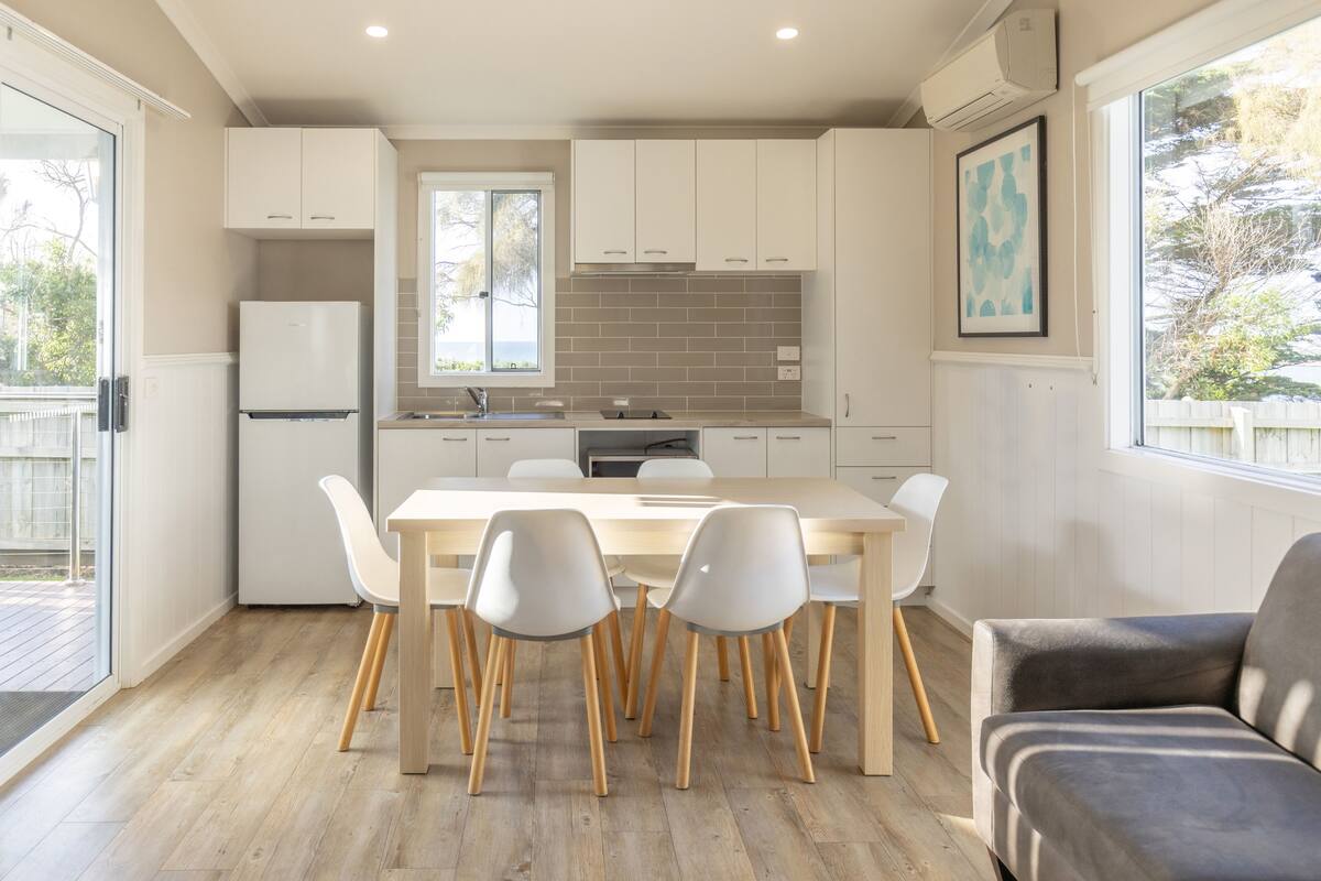 A modern kitchen with white cabinets, a wooden dining table, and chairs.