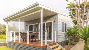 A modern house with a covered porch, a dining area with outdoor furniture, and a small staircase leading to the entrance. - NRMA Portland Bay Holiday Park (Portland)