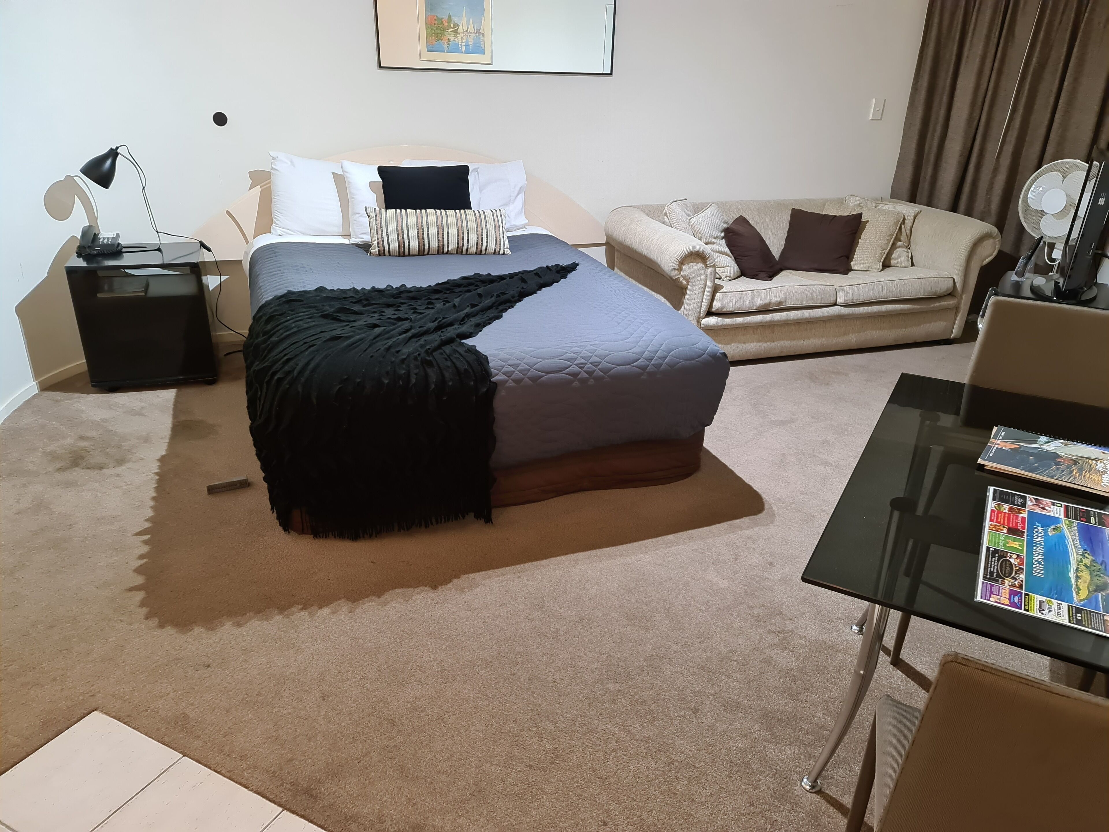 A bedroom with a bed, bedside table, lamp, and a chair.