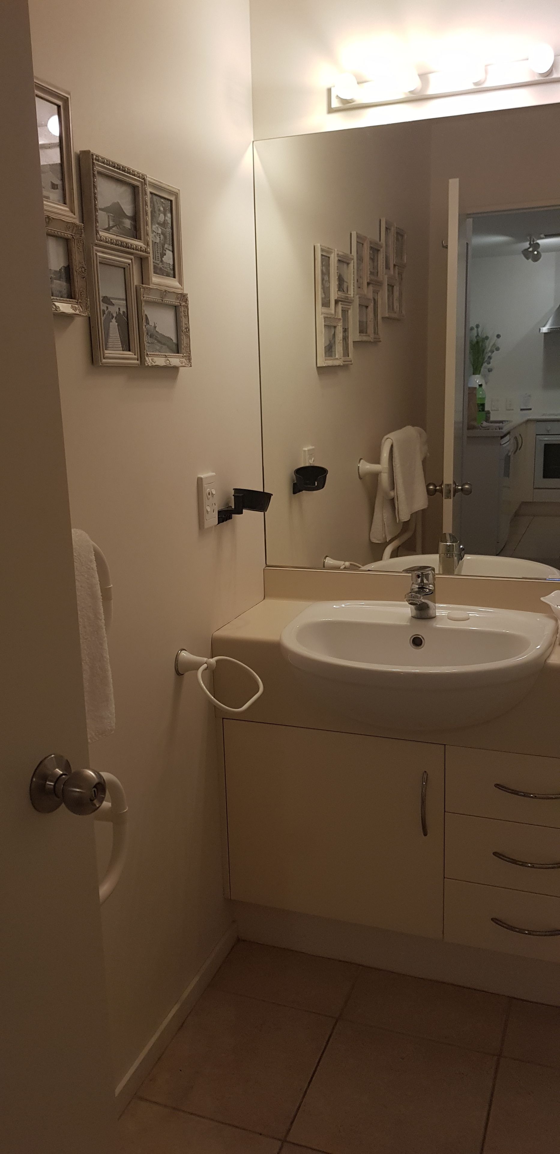 A bathroom with a sink, mirror, and framed pictures on the wall.