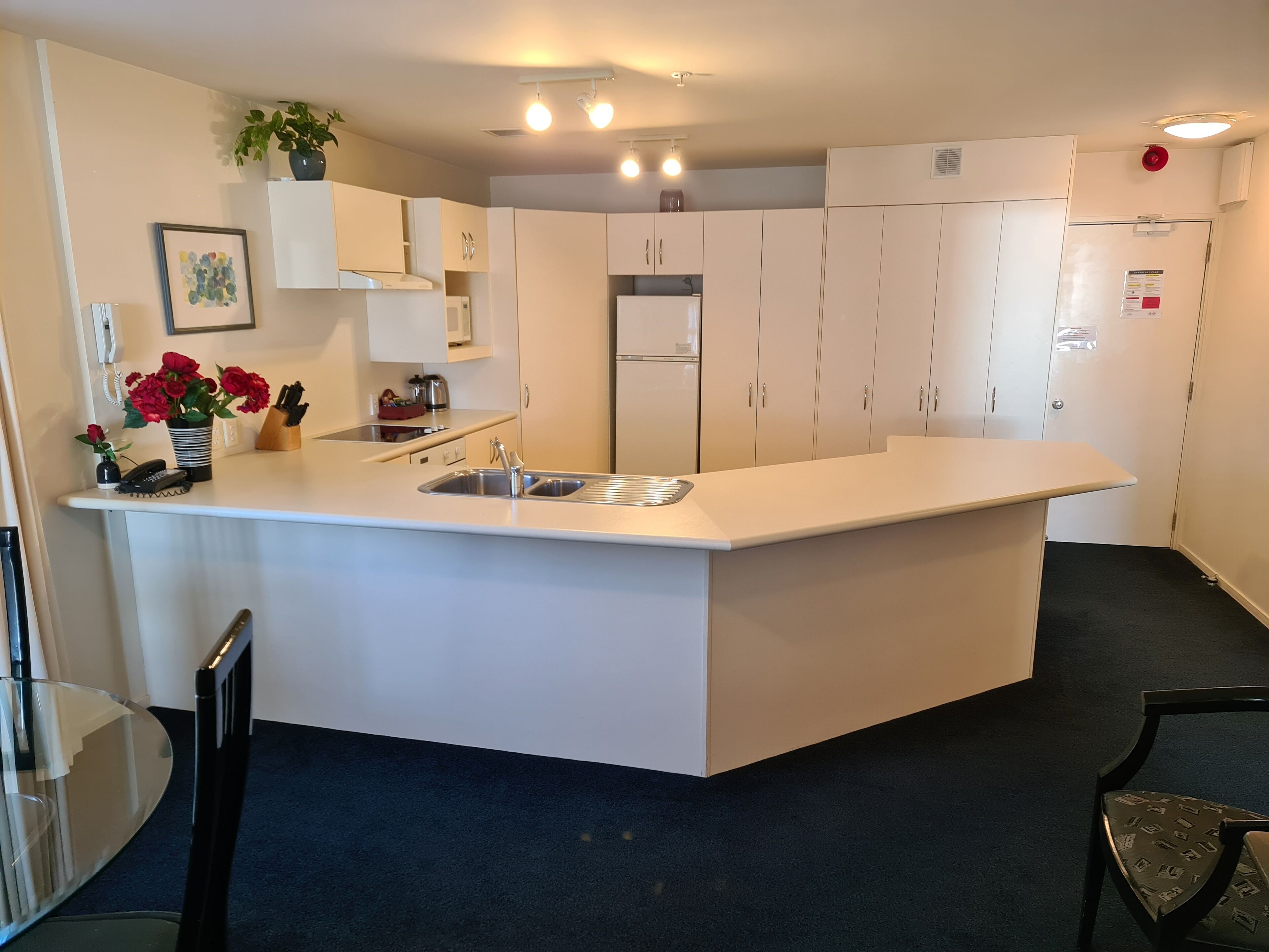 Une cuisine moderne dotée d’un îlot central, de meubles blancs et d’un évier encastré.