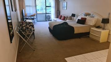 Une chambre d’hôtel avec un lit, une table de chevet, une lampe et une vue sur l’extérieur par une fenêtre.