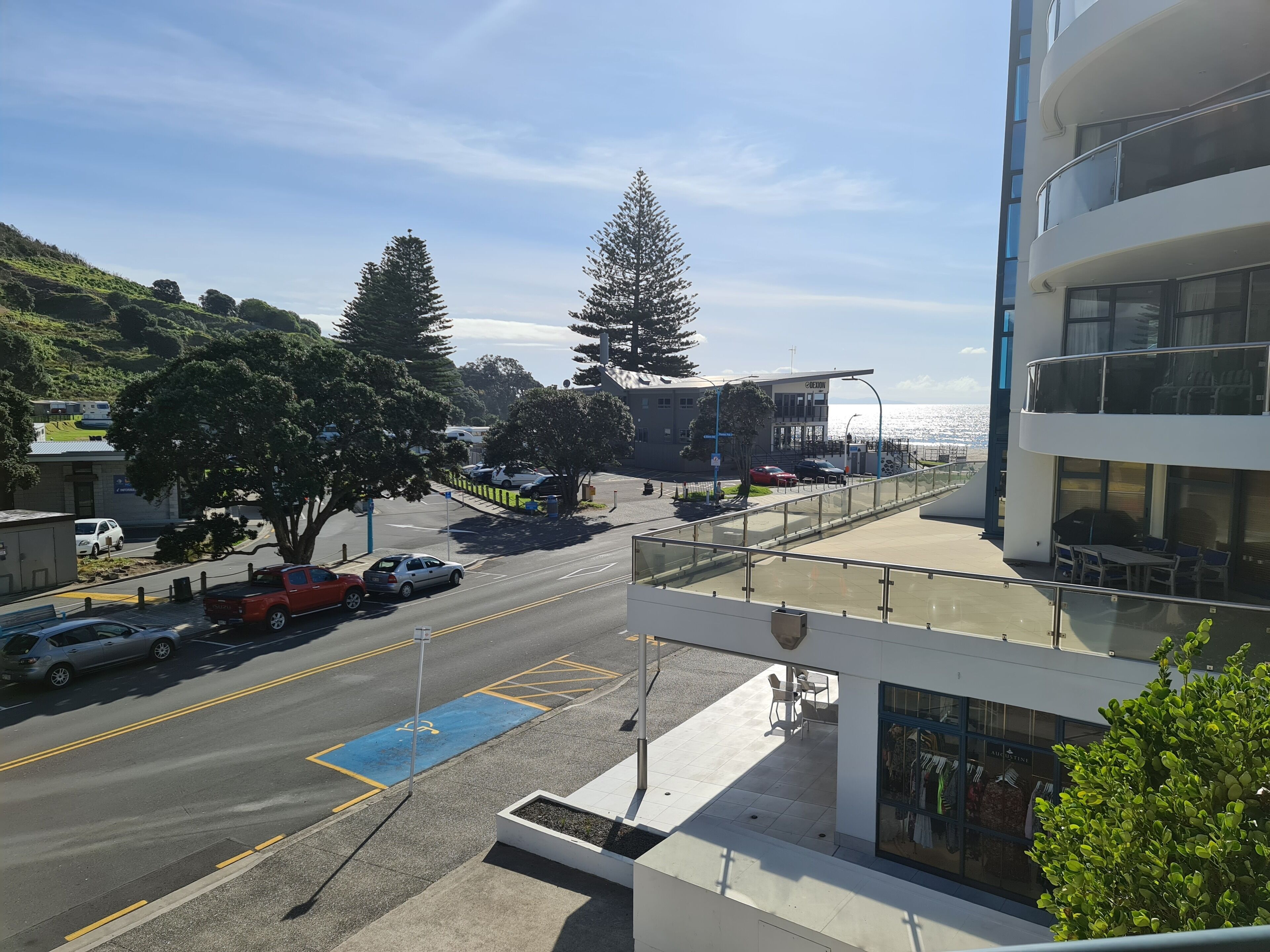 Vista costera con un edificio moderno, un área de estacionamiento y cielo despejado.