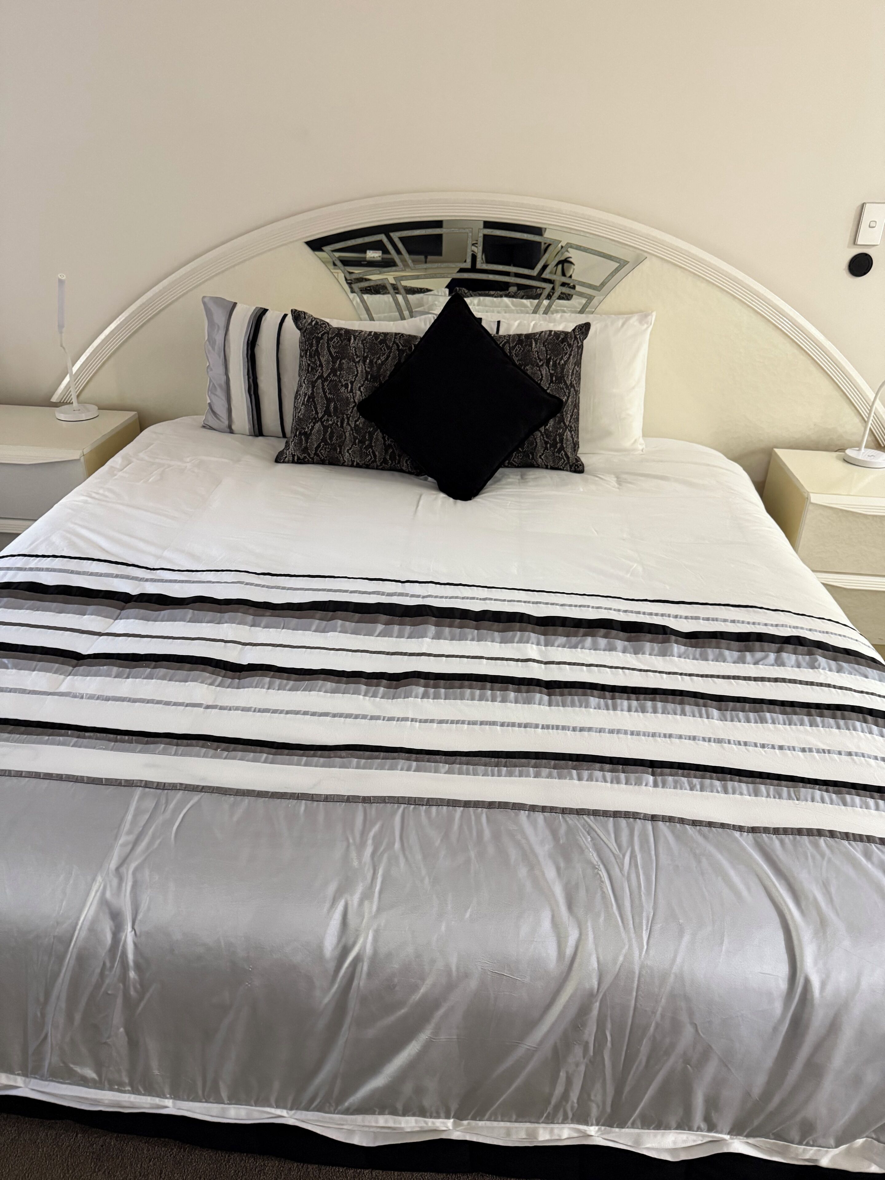 A bed with a white headboard, multiple pillows, and a striped bedspread.