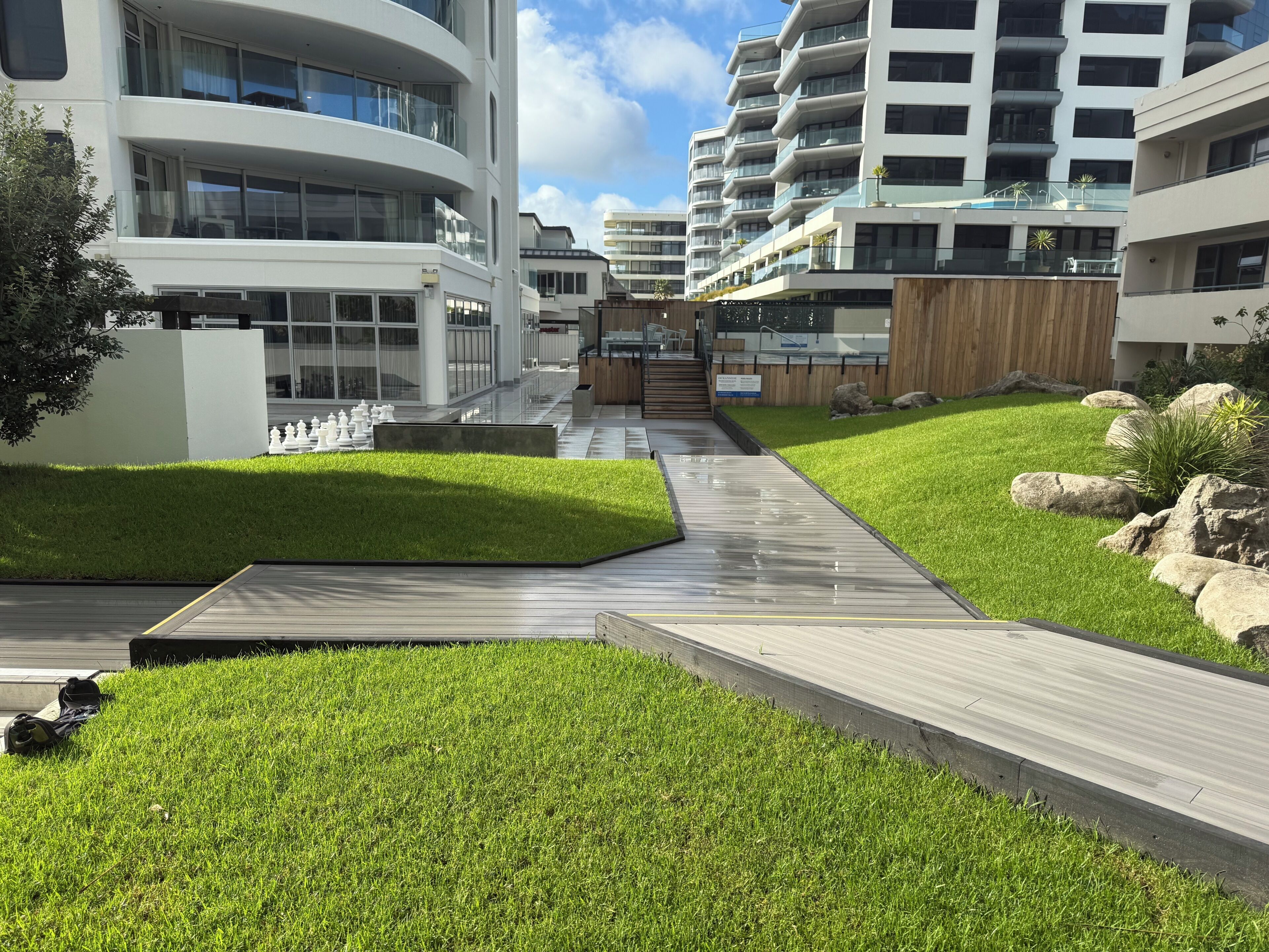 Un bâtiment moderne doté d’un chemin central, entouré de pelouses bien entretenues et d’une terrasse en bois.