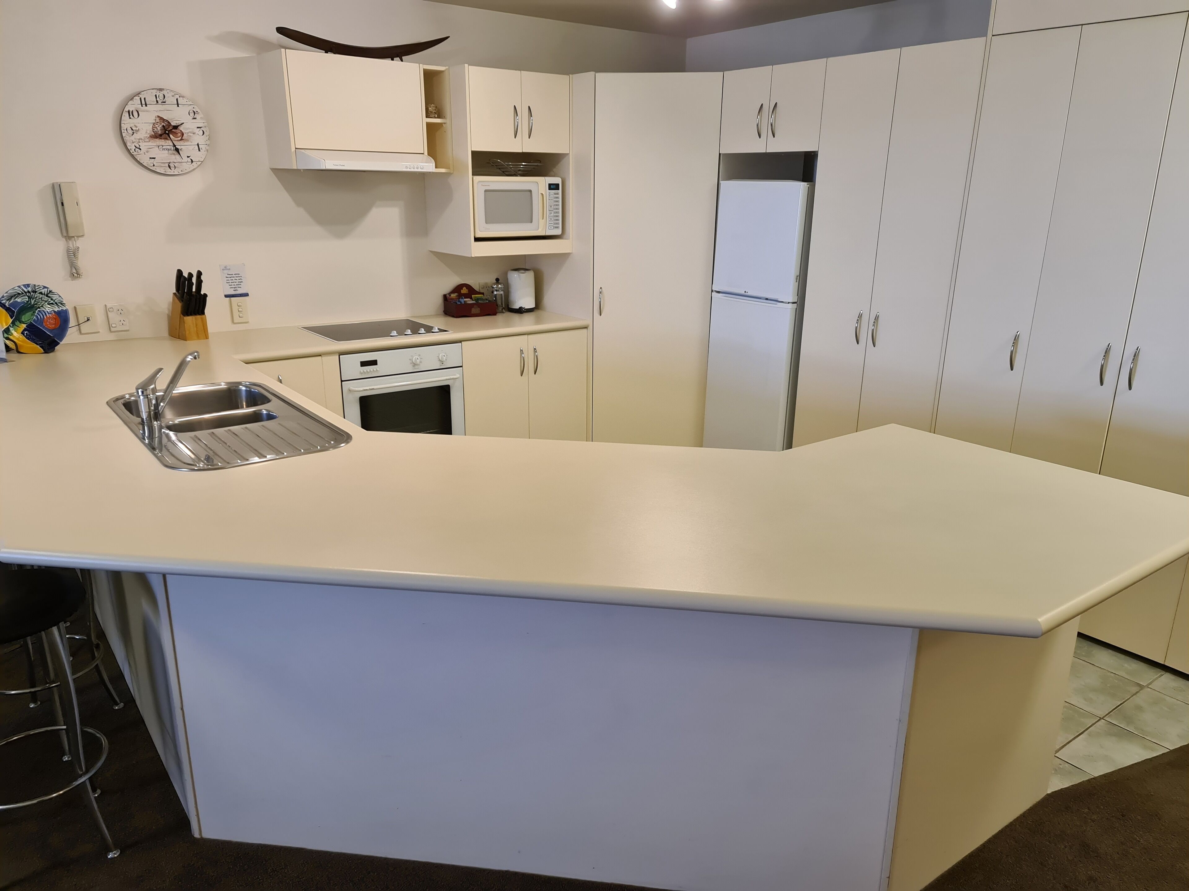 A modern kitchen with white cabinetry, a stainless steel sink, a microwave, and a refrigerator.
