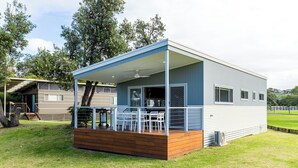 Een moderne stacaravan met een overdekte veranda, een klein terras en een omheinde tuin.