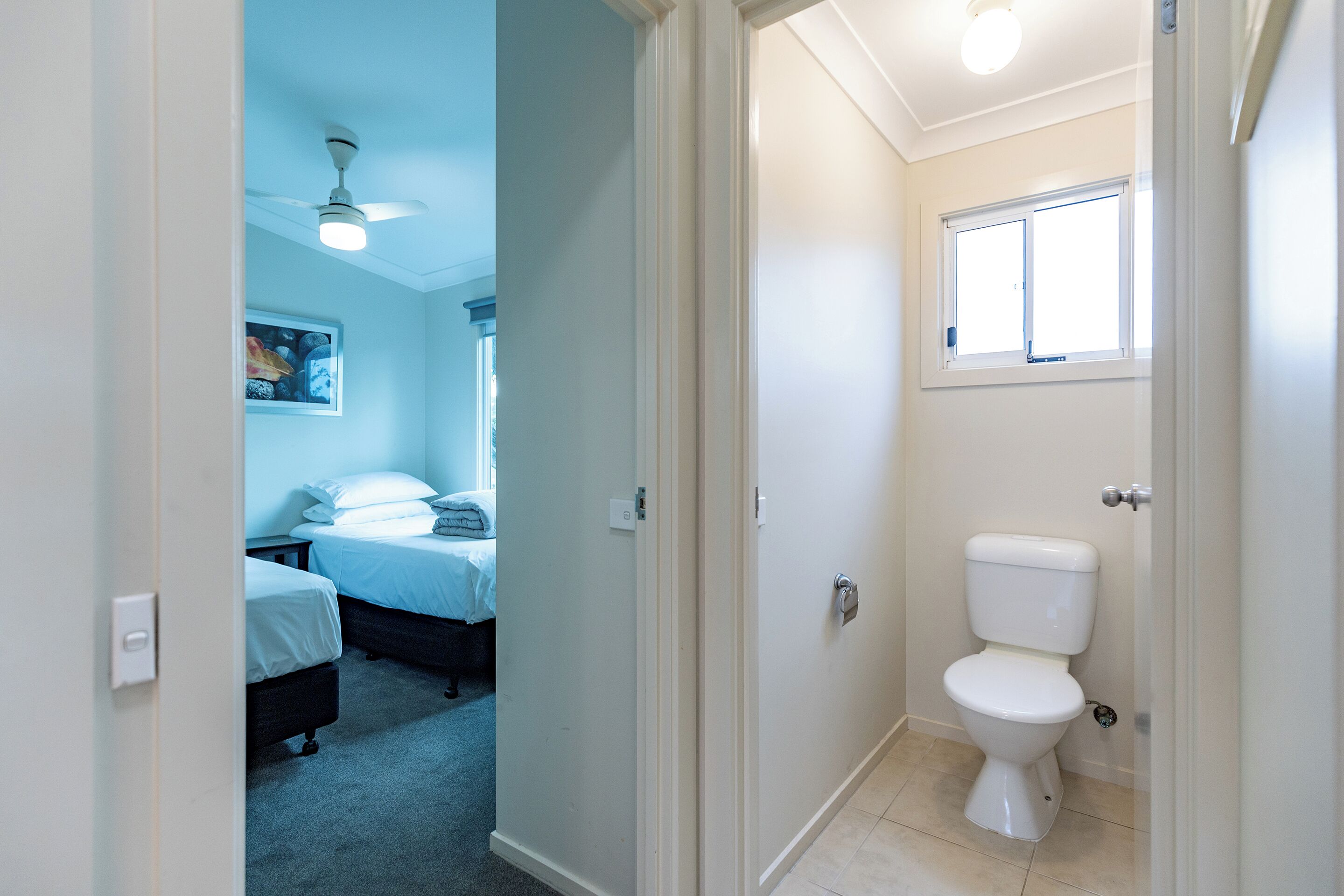 A bedroom with two beds, a nightstand, and a ceiling fan.
