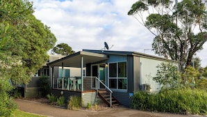 Een modern, gelijkvloers huis met een overdekte veranda, grote ramen en een schotelantenne.