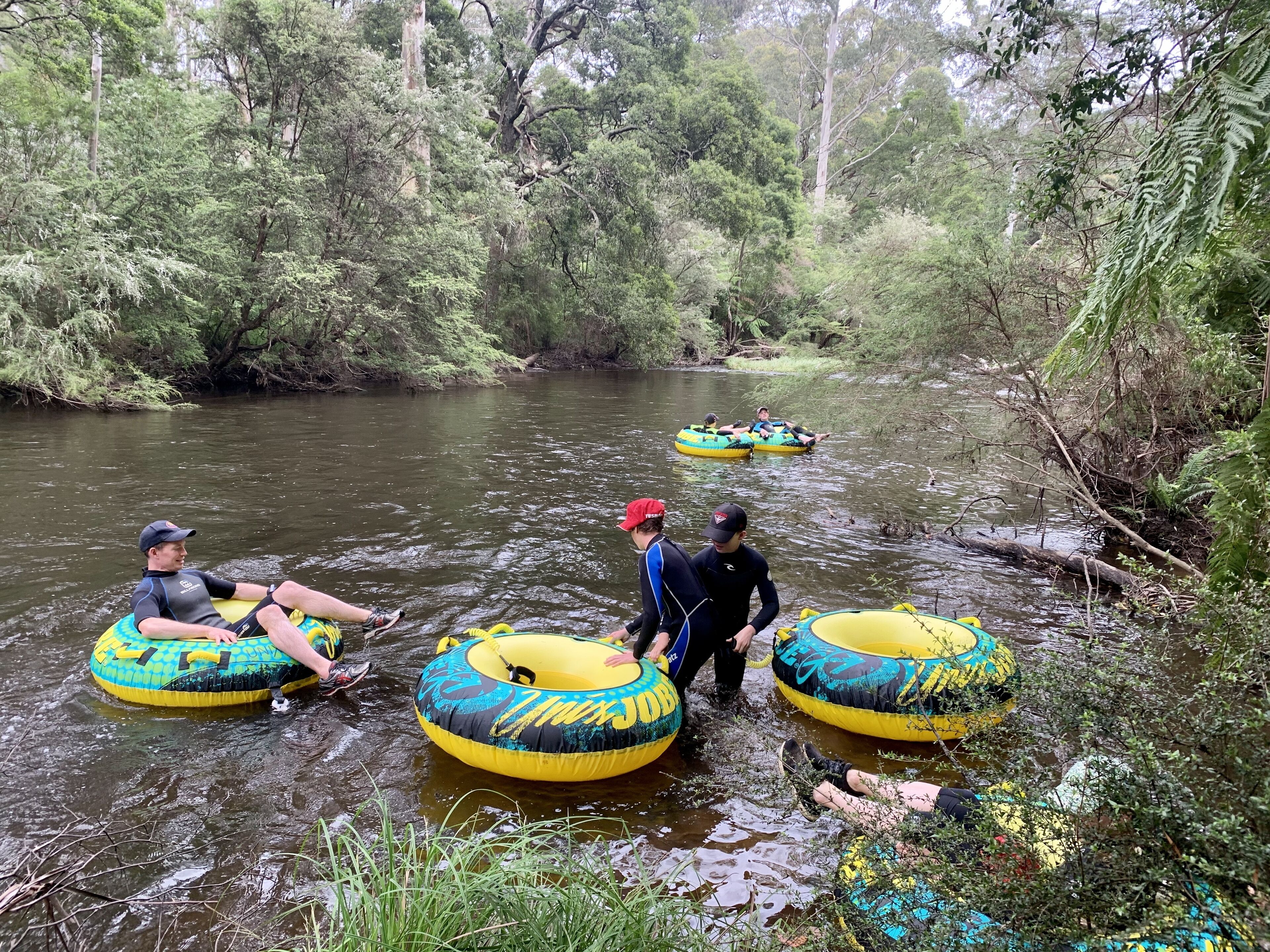 Des personnes flottent sur des bouées gonflables dans une rivière, entourée d’une végétation luxuriante.