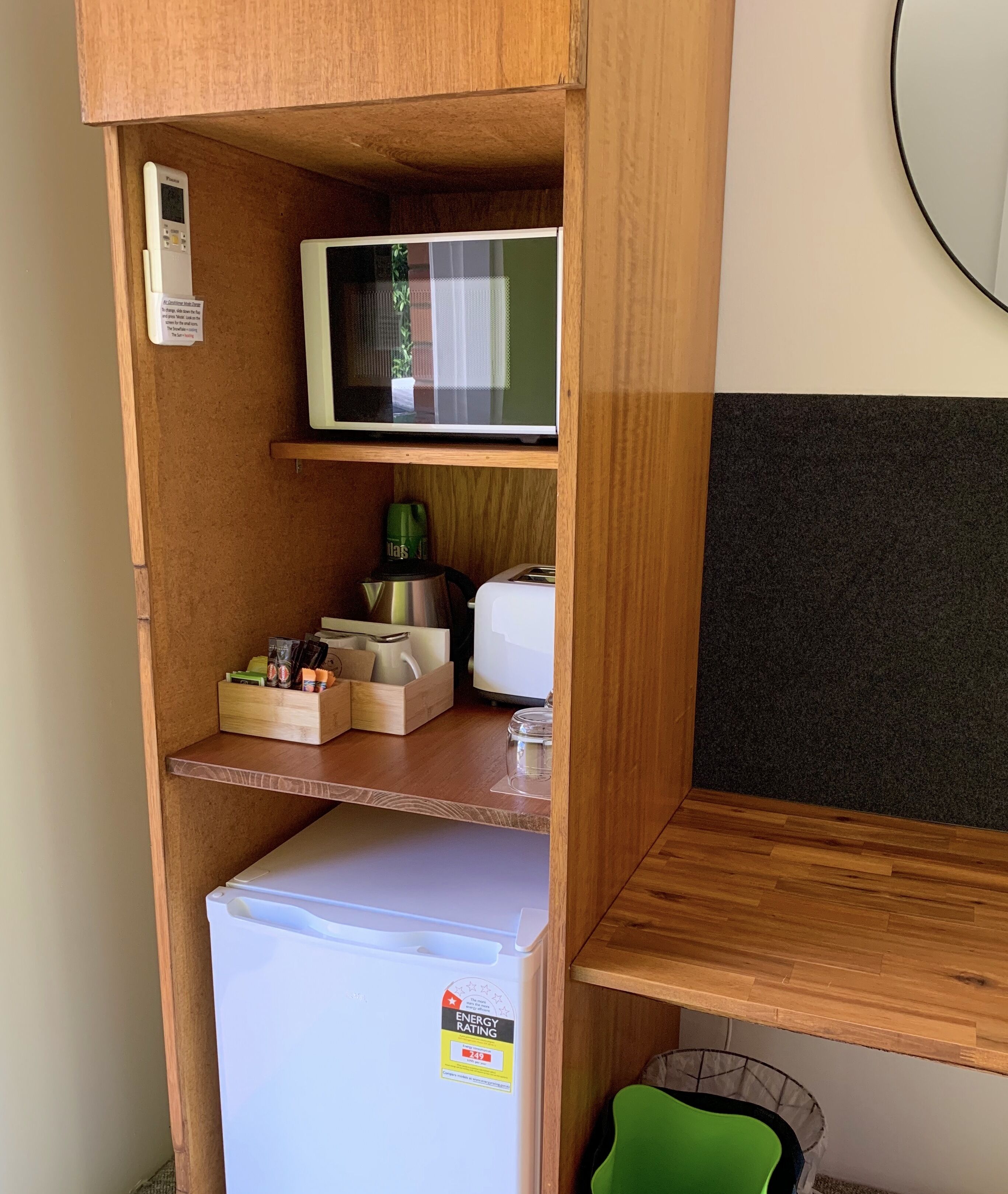 A compact kitchenette with a microwave, refrigerator, and various kitchen items.