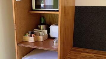 A compact kitchenette with a microwave, refrigerator, and various kitchen items.