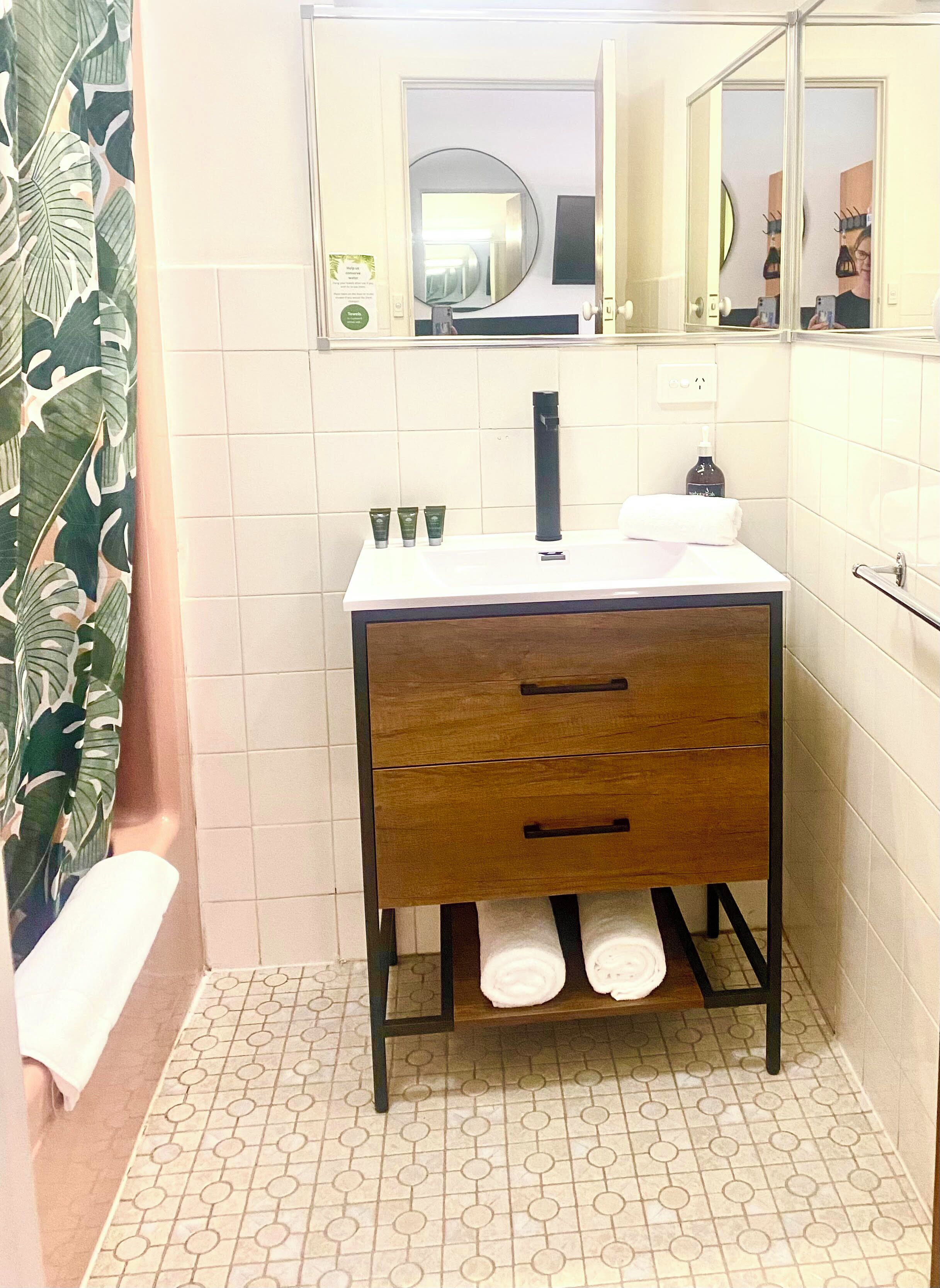 A bathroom with a wooden vanity, a mirror, a sink, and a toilet.