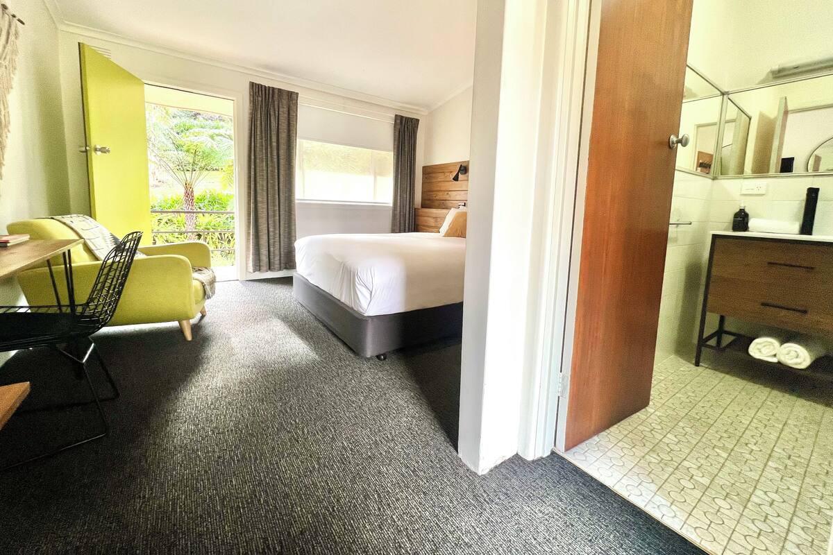 Une chambre d’hôtel comprenant un lit, un bureau, une chaise, une commode et une salle de bain.