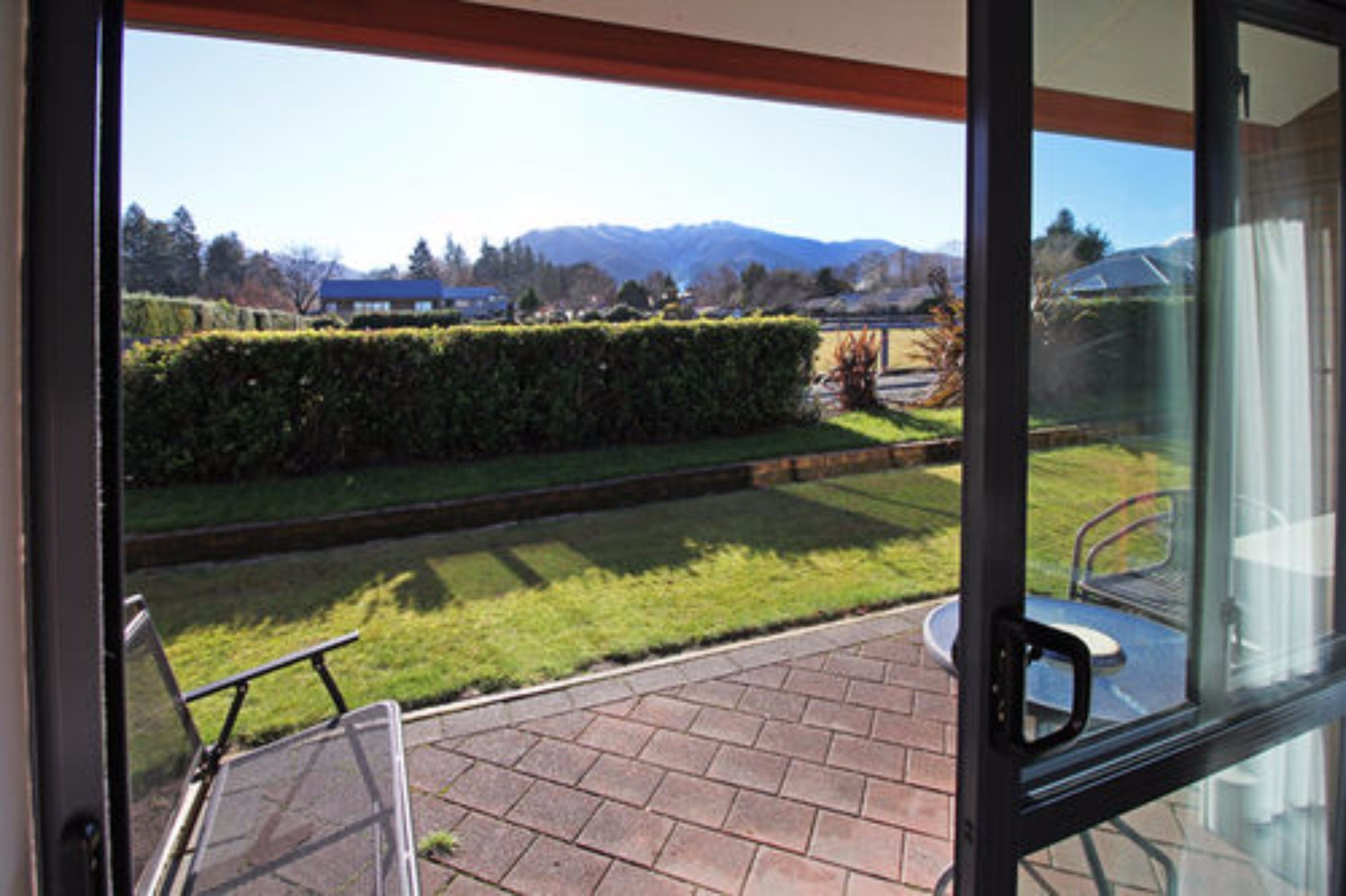 A patio with a view of a well-maintained lawn and distant mountains.