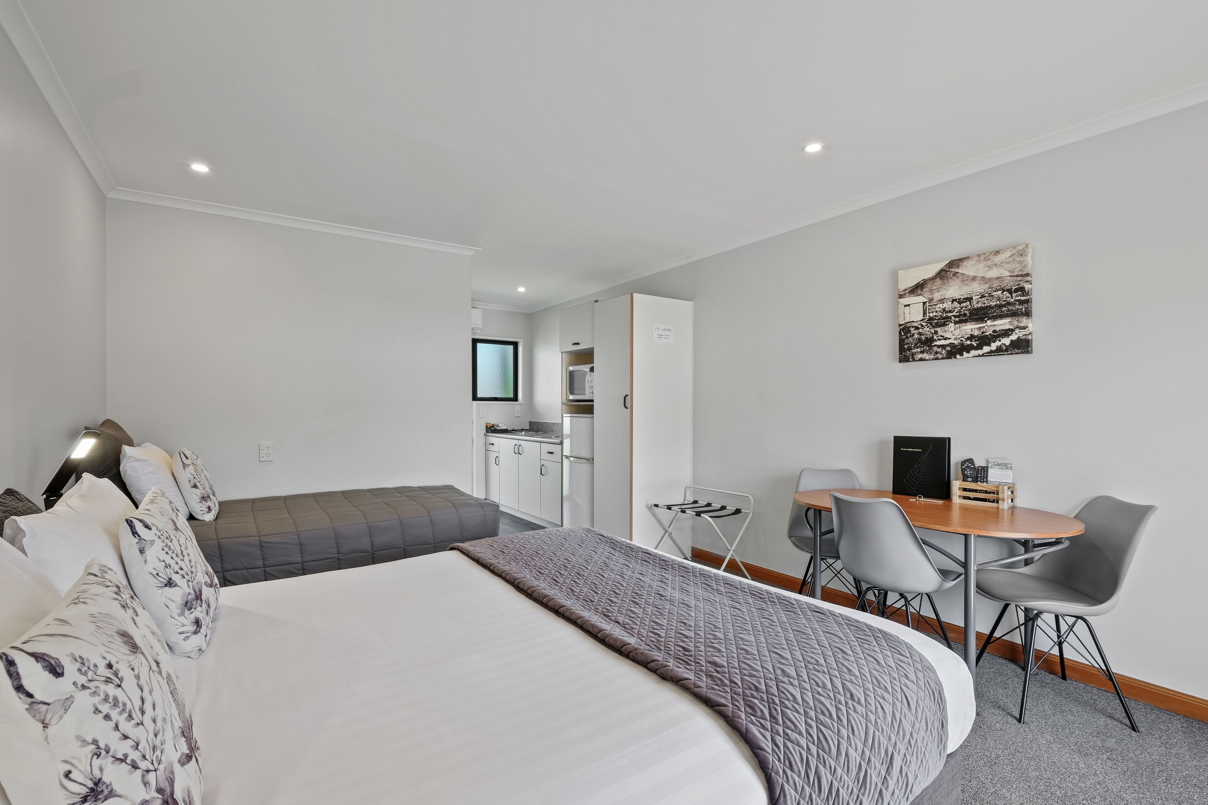 Une chambre d’hôtel moderne dotée d’un grand lit, d’un coin salon avec une table et des chaises, d’une kitchenette et d’un coin repas.