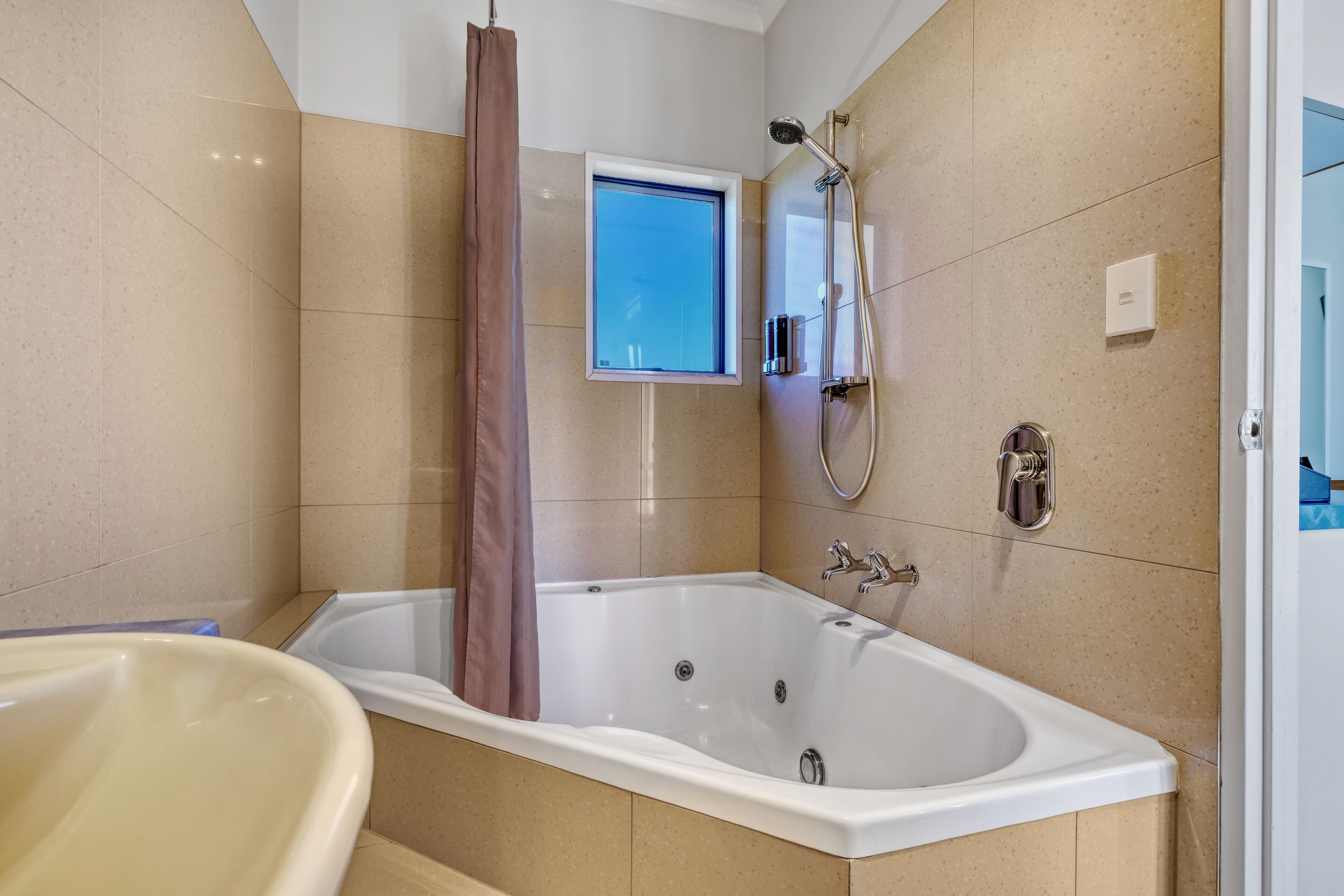 A modern bathroom with a bathtub, a shower, and a window.