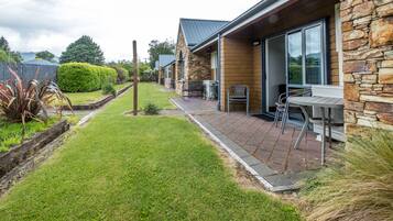 A house with a stone exterior, a paved patio with outdoor furniture, and a well-maintained lawn.