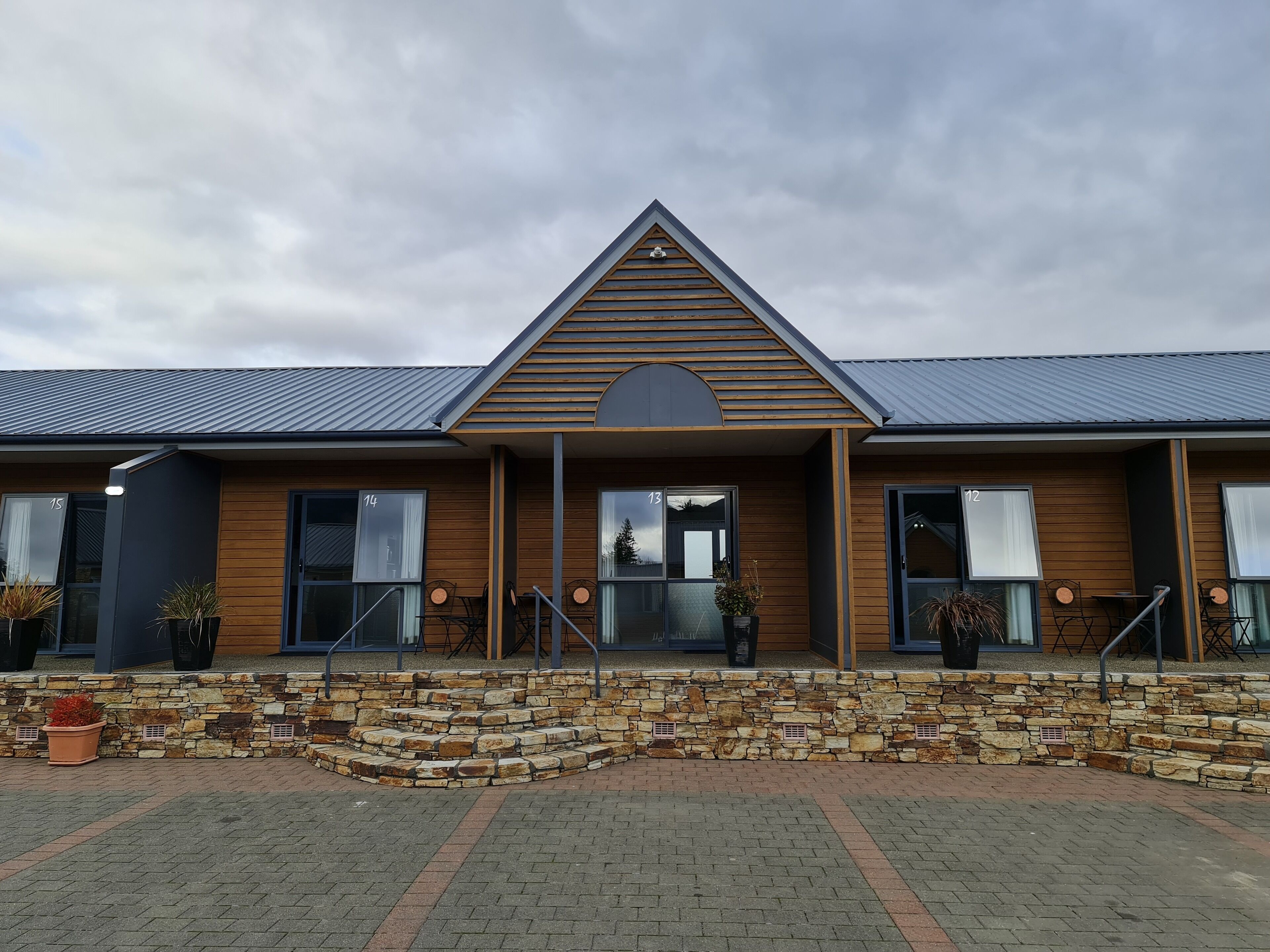 A modern building with a stone facade, wooden trim, and a triangular roof.