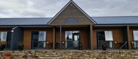 A modern building with a stone facade, wooden trim, and a triangular roof.