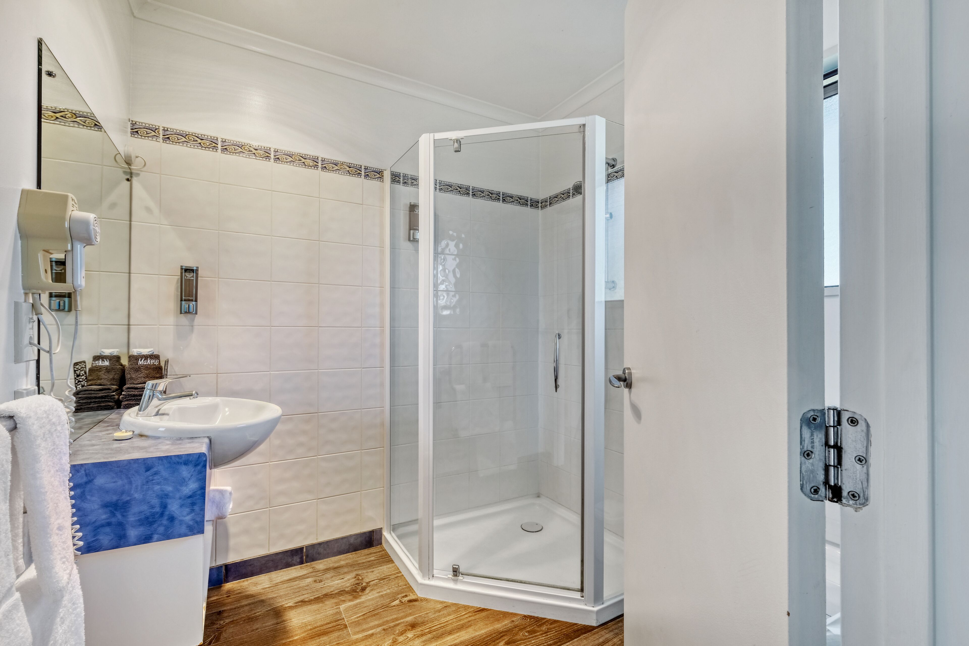 A modern bathroom with a glass-enclosed shower, a sink, and a mirror.