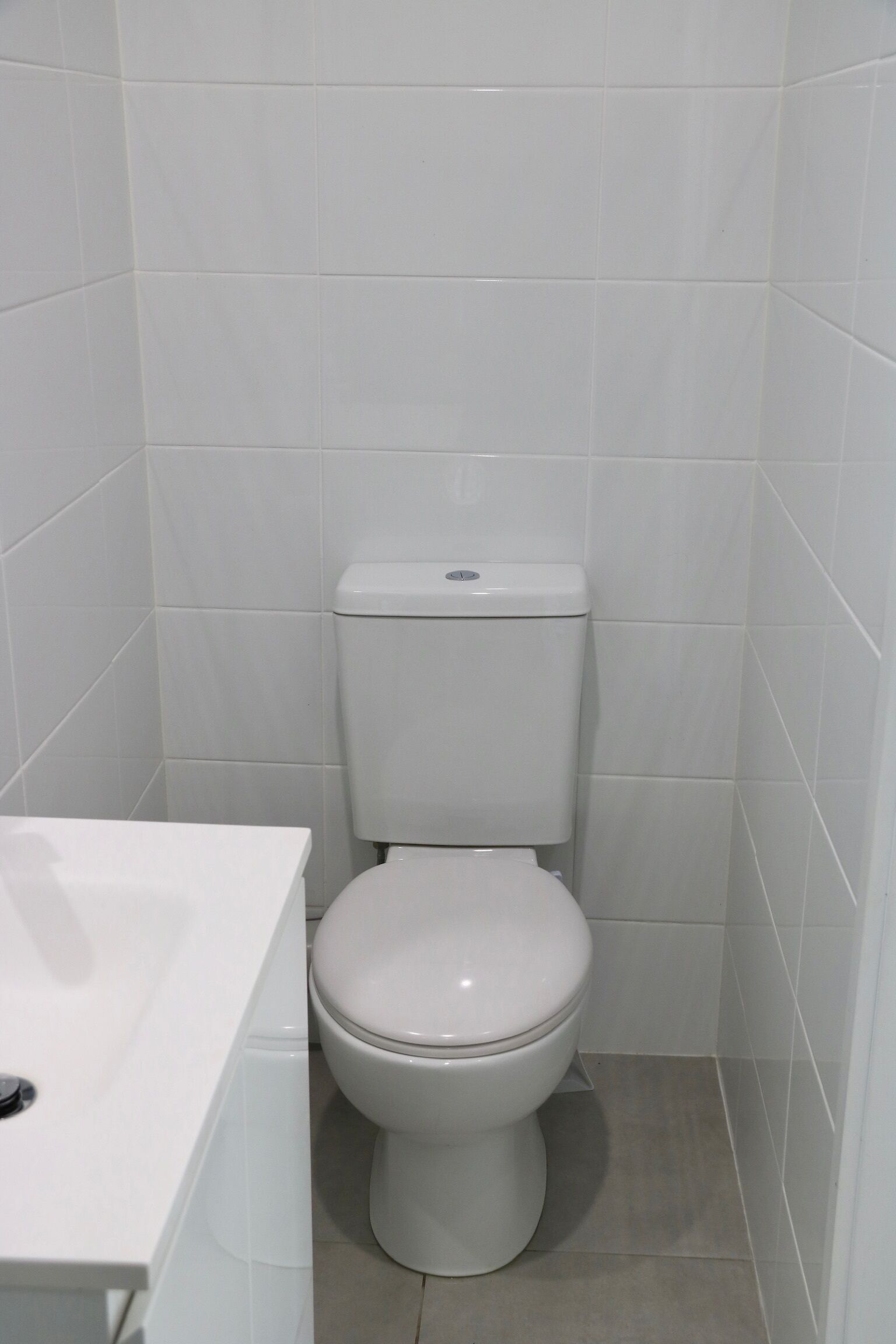 A small, white bathroom with a toilet and a sink.